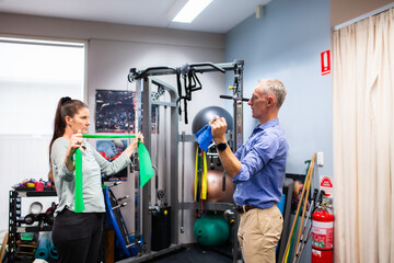 Woman working with physio at physiotherapist clinic using equipment to recover from injury