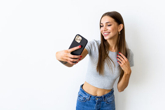 Portrait of a smiling woman making selfie photo on smartphone isolated on a white background
