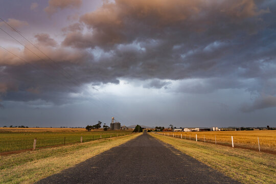Wide angled view of a colourful dramatic stormfront over a country road