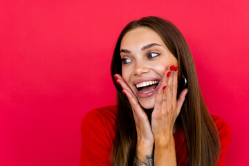 Screaming excited young woman standing isolated over red background.