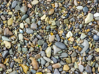 Small round stones background. Stone texture. Rough surface of small pebble stone.Small smooth pebbles, translucent colored minerals