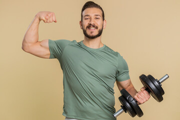 I am strong. Athlete sportive man showing biceps and looking confident, feeling power strength, energy to gain success win, motivation. Middle eastern sportsman guy with dumbbell on beige background