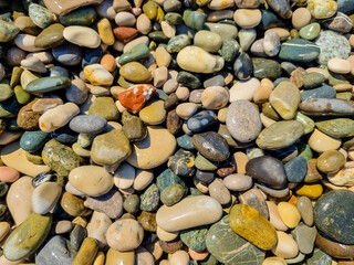 Small round stones background. Stone texture. Rough surface of small pebble stone.Small smooth pebbles, translucent colored minerals