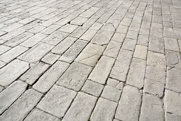 Old and damaged italian paving made with chiseled grey sandstone