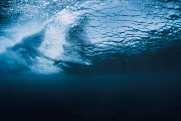 Wave underwater and surfer on surfboard in ocean. Underwater crashing wave and surfboard in...