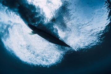Surfer on surfboard underwater view. Crashing wave and surfboard