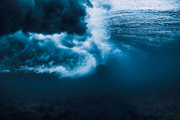 Wave underwater and surfboard in ocean. Underwater view of crashing wave in transparent water