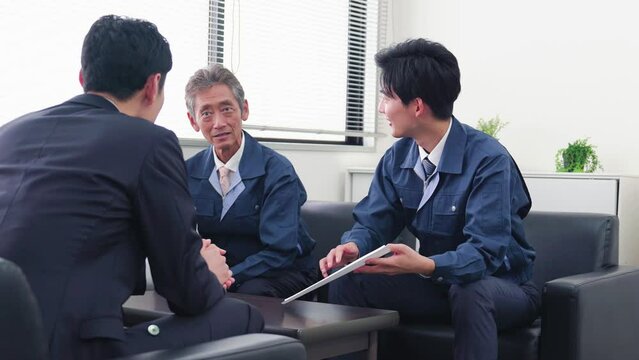 作業服の男性とミーティングをするビジネスマン