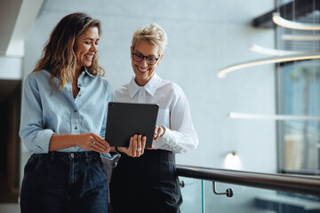 Female executive assistant using a tablet to show her boss a positive business report