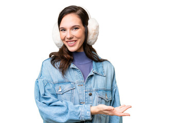 Young caucasian woman wearing winter muffs over isolated background presenting an idea while looking smiling towards