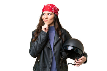 Young caucasian woman with a motorcycle helmet over isolated background having doubts and thinking