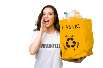 Young caucasian woman holding a bag full of plastic bottles to recycle over isolated background shouting with mouth wide open