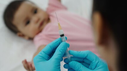 doctor holding syringe and preparing vaccine giving injection to infant baby