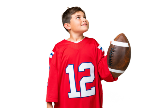 Little caucasian kid playing rugby over isolated chroma key background looking up while smiling