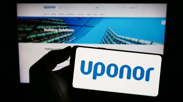 Stuttgart, Germany - 06-18-2023: Person holding smartphone with logo of Finnish water technology company Uponor Oyj on screen in front of website. Focus on phone display.
