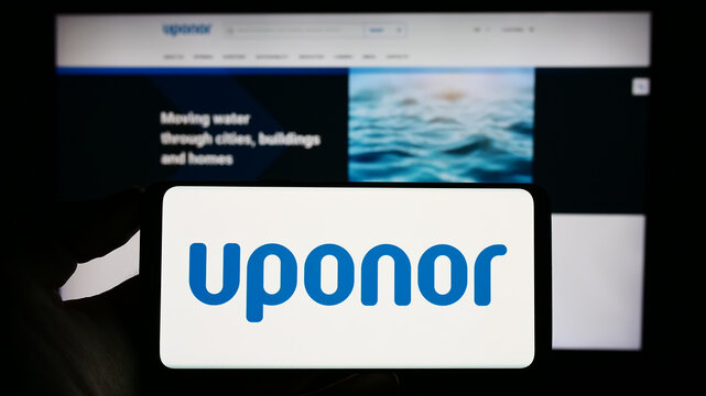 Stuttgart, Germany - 06-18-2023: Person holding cellphone with logo of Finnish water technology company Uponor Oyj on screen in front of business webpage. Focus on phone display.