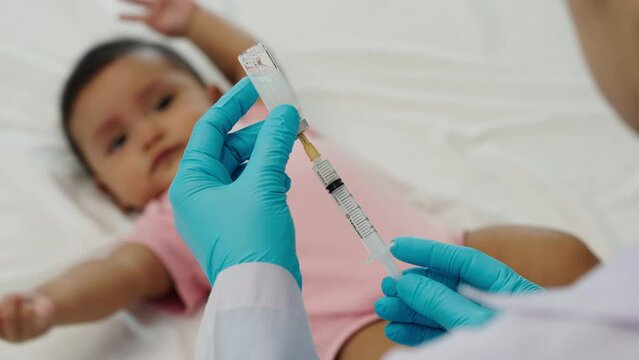 doctor drawing syringe and preparing vaccine giving injection to infant baby