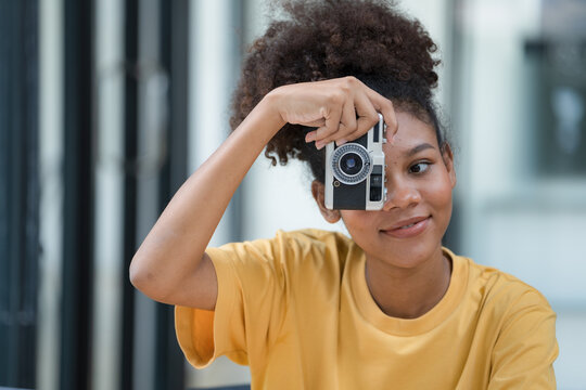 A beautiful African American girl taking photos with a retro film camera.