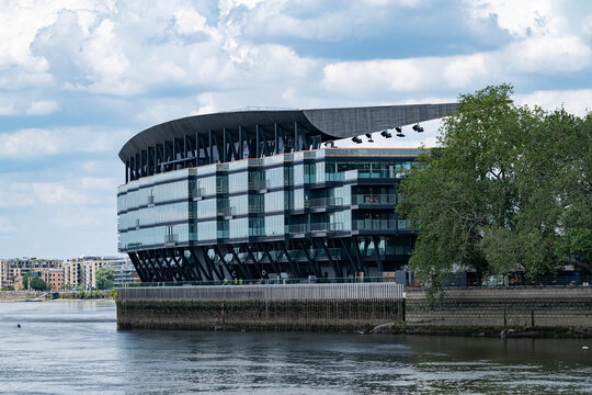 Fulham Football Clubs Craven Cottage stadium, view of the back of the new stand shot from the opposite bank of the river thames with light white clouds overhead
