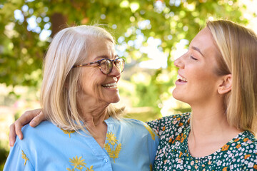 Multi-Generation Family With Senior Mother Wearing Glasses  And Adult Daughter Laughing In Garden 