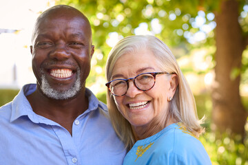 Portrait Of Loving Multi-Racial Senior Couple Standing Outdoors In Garden Park Or Countryside