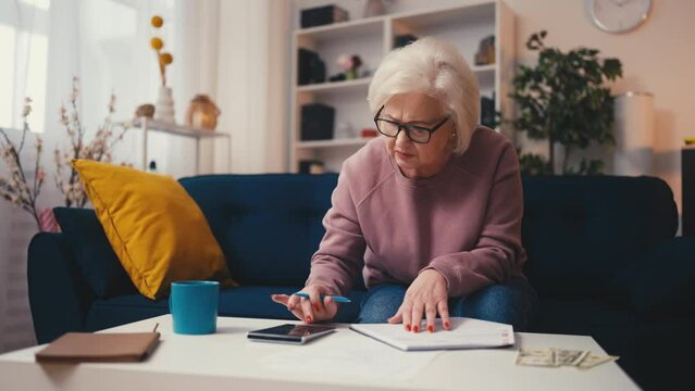 Concentrated senior woman calculating family budget, planning expenses, taxes