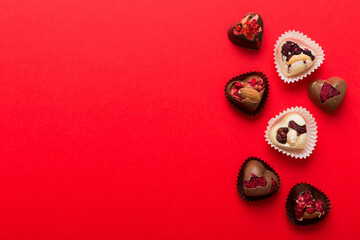 chocolate sweets in the form of a heart with fruits and nuts on a colored background. top view with space for text, holiday concept