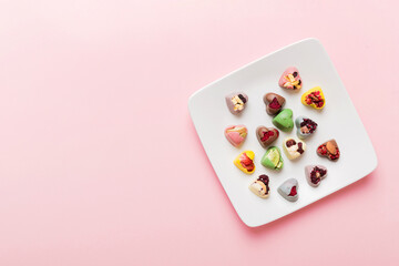 Plate with different chocolate on colored background. Assortment of fine chocolates top view vith copy space Health and obesity concept