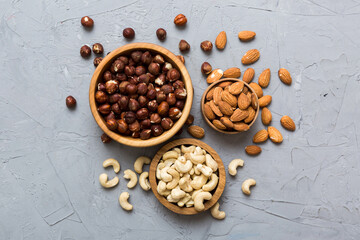 Assortment of nuts in wooden bowl on colored table. Cashew, hazelnuts, walnuts, almonds. Mix of nuts Top view with copy space