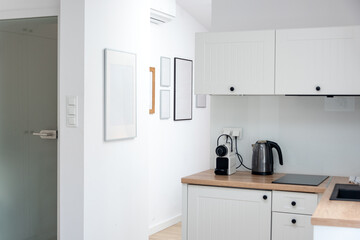 Interior design of modern trendy white kitchen and studio living room in minimalistic scandinavian style. Rent of modern flat or sale of a new apartment, modern home renovation. 
