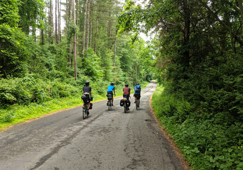 Obraz premium four touring cyclists riding on empty quiet country road (gravel ride, adventure cycling)