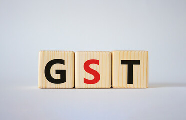 GST - Goods and Services Tax symbol. Concept word GST on wooden cubes. Beautiful white background. Business and GST concept. Copy space.