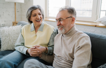 Happy senior couple laughing while sitting on sofa