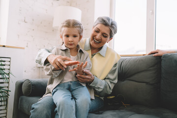 Happy grandmother playing with cute granddaughter