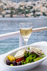 Greek Salad Served with a Glass of Local Wine on a Restaurant Table Over the Mediterranean Sea in Symi Greece