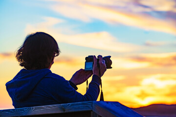 Woman with camera take travel photo at sunset