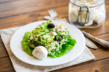 fresh summer salad with early cabbage, cucumbers, radishes and other vegetables in a plate