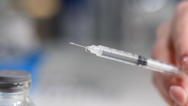 medical syringe for injection with medicine, drops drip from the needle, close-up