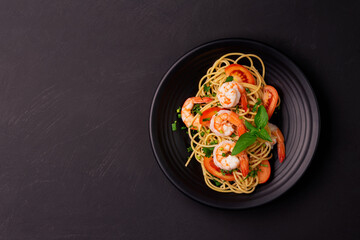 Stir-fried spaghetti or stir-fried noodles Tomato sauce and prawns on a black plate On a wooden table background. Top view. - Powered by Adobe
