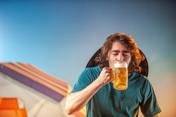 young man with glass of draft beer against sunset background