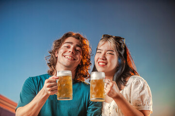 Interracial friends toasting draft beer against the sunset.