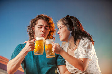 Interracial friends toasting draft beer against the sunset.