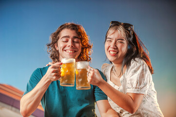 Interracial friends toasting draft beer against the sunset.