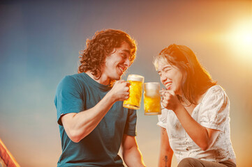 Interracial friends toasting draft beer against the sunset.