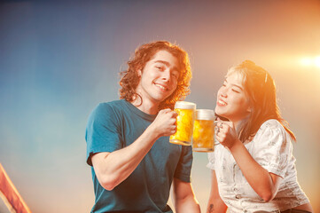 Interracial friends toasting draft beer against the sunset.