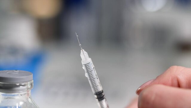 vaccination, a syringe with a needle and medicine inside, drops of vaccine flow down from glans, close-up