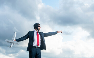 executive in suit and pilot hat launch plane toy on sky background