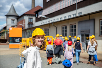Portrait happy woman tourist wear yellow safety helmet equipment at Rammelsberg Unesco Mine trip entrance group tour. Tourism at industrial miner area Goslar Harz, Germany. Extreme mountain adventure - obrazy, fototapety, plakaty