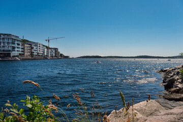 Norwegen im Sommer: Idyllische Szenerie in der Nähe des Yachthafens von Kristiansand im südlichen Norwegen mit blauem Himmel, Natur und einigen Häusern strahlendem Sonnenschein, Copy Space