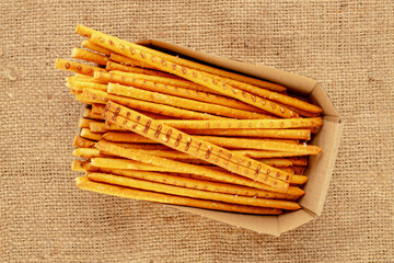 Straw is a bakery product. Several straws with a paper plate on a jute cloth, macro, top view.
